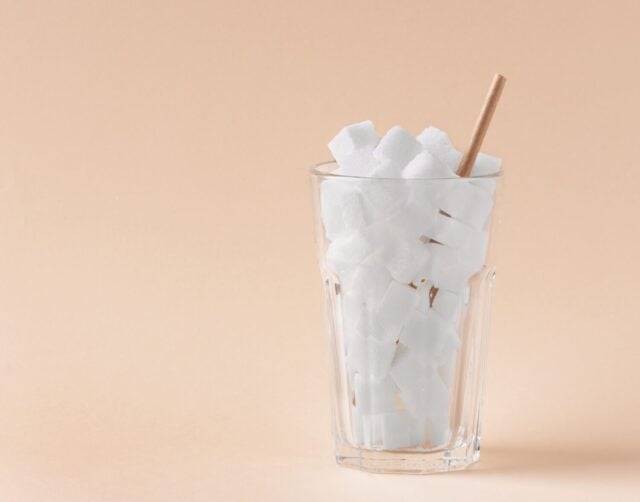 Glass full of sugar cubes. Unhealthy food and drink concept. Concept of too much sugar in drinks.