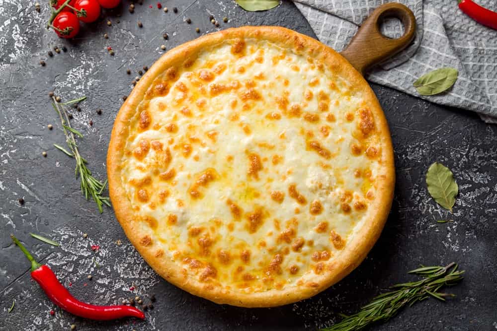 Cheese pizza on board on dark stone table top view