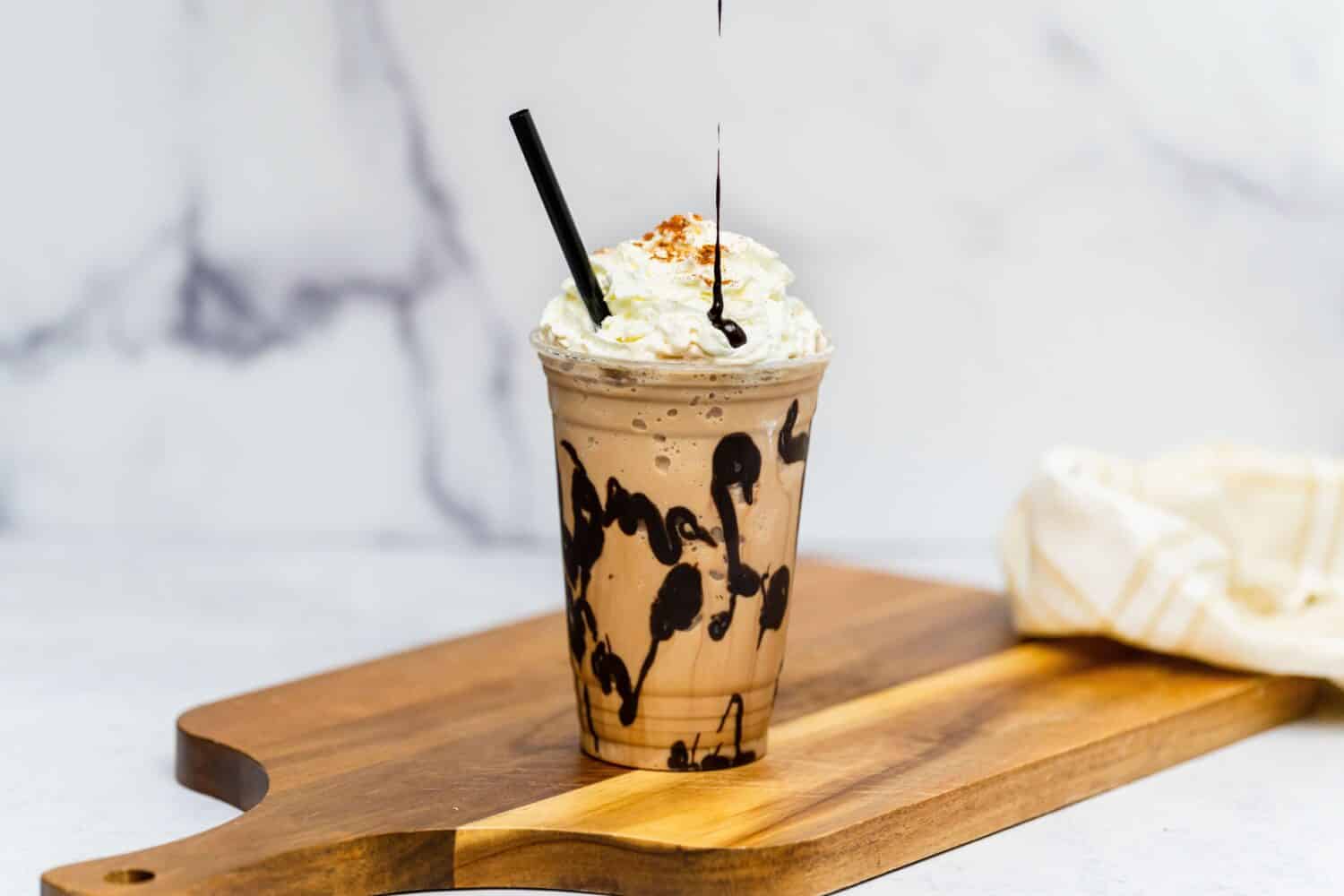 A tasty fresh Frappuccino with cream served on the wooden board