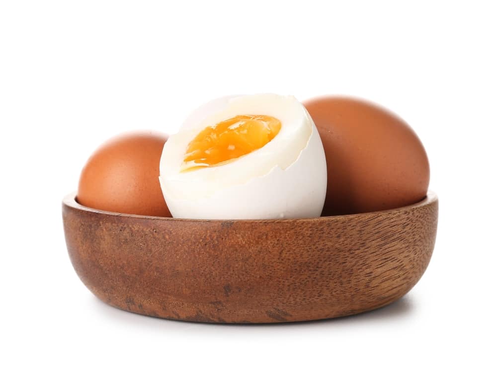 Bowl with soft boiled eggs on white background