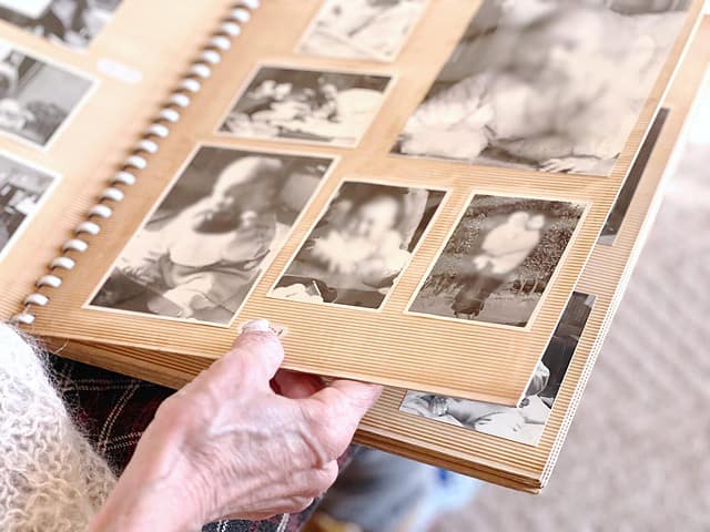 Elderly woman's hand looking at black and white photo album