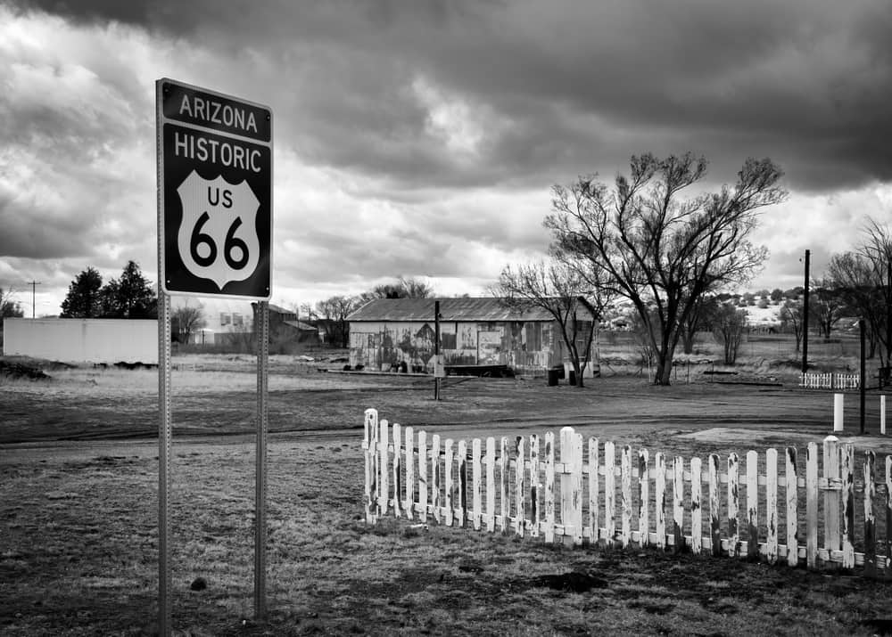 A white picket fence stands next to a sign for historic Route 66 stands in rural Ash Fork, Arizona.