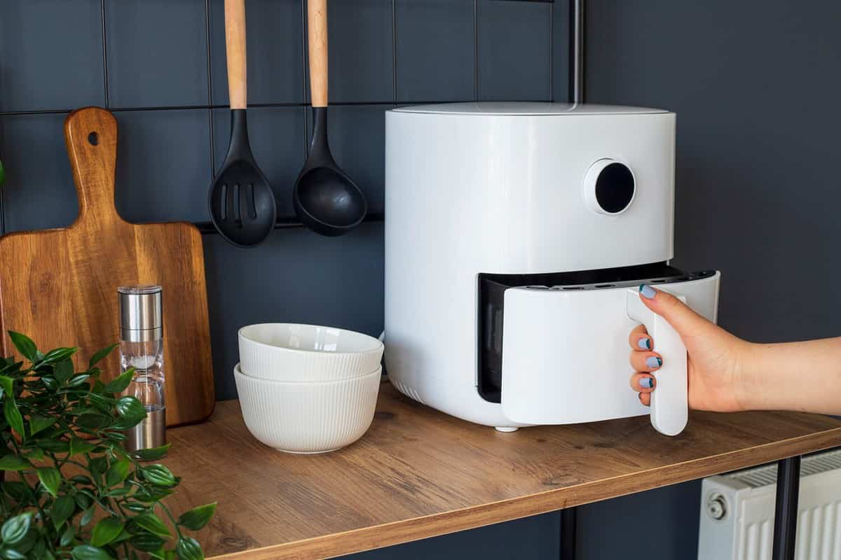 Woman at home using an air fryer. Making healthy food, frying without the use of oil