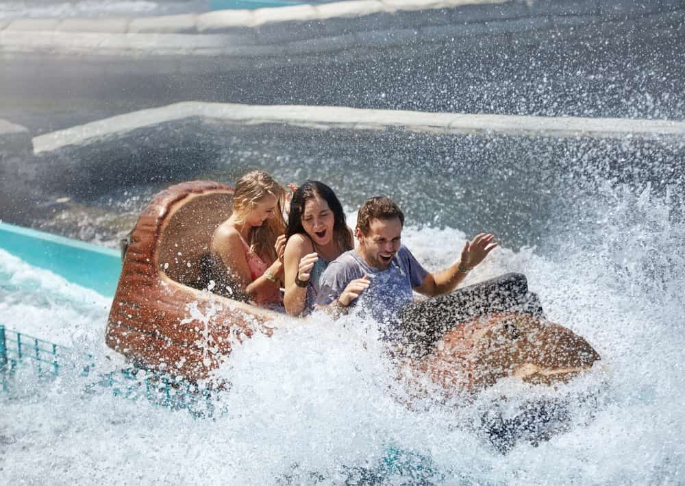 Friends getting splashed in water log amusement park ride