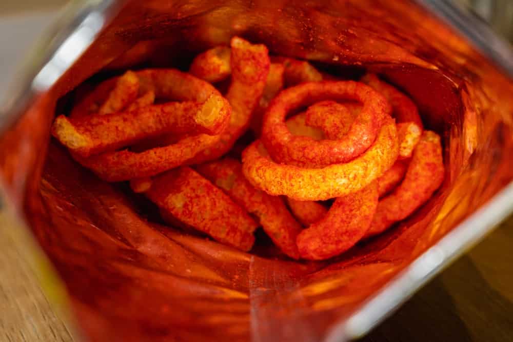 Spicy red colored onion flavored rings inside a snack bag.
