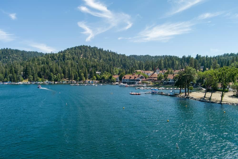 aerial shot of a gorgeous summer landscape at Lake Arrowhead with rippling blue water, boats sailing, boat docks and mountains covered in lush green trees in Lake Arrowhead California USA