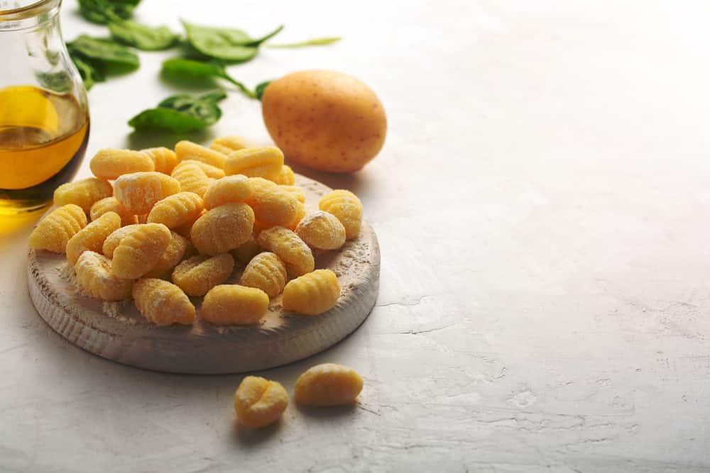 Raw italian gnocchi on a white background with potato and olive oil copy space. Gnocchi is Italian, but also South German and Austrian dish.