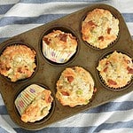 Fresh baked bacon cheddar muffins in old muffin tin on blue and whit striped teacloth in flat lay composition. Healthy breakfast or snack.
