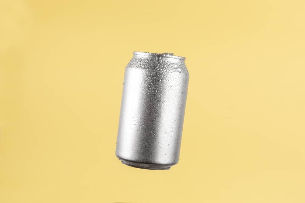 Aluminium beer or soda drinking can on light yellow background