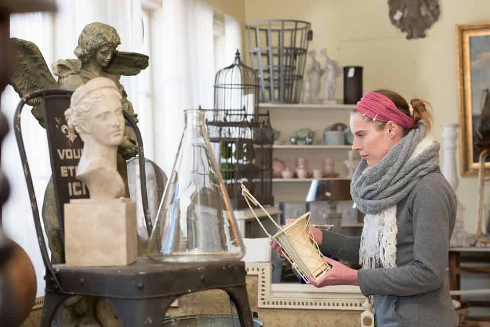 Attractive woman visiting an antique shop and looking for precious nice things