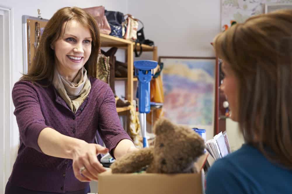 Woman Donating Unwanted Items To Charity Shop