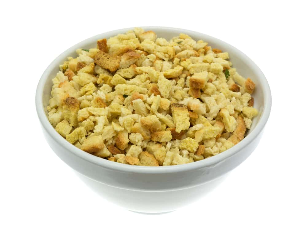 An old bowl filled with crumbled dry stuffing mix isolated on a white background.