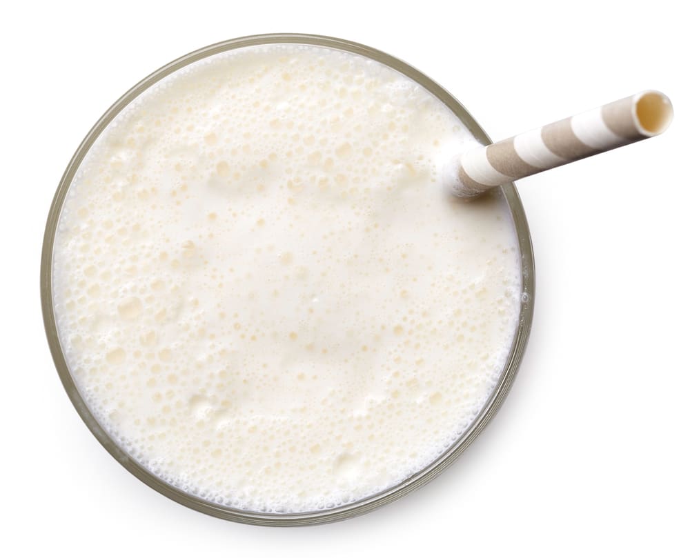 Glass of vanilla milkshake isolated on white background from top view