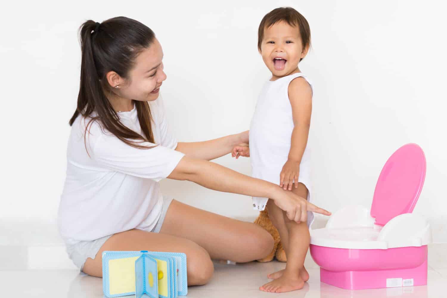 Mother pointing at potty, child happy at succeeding