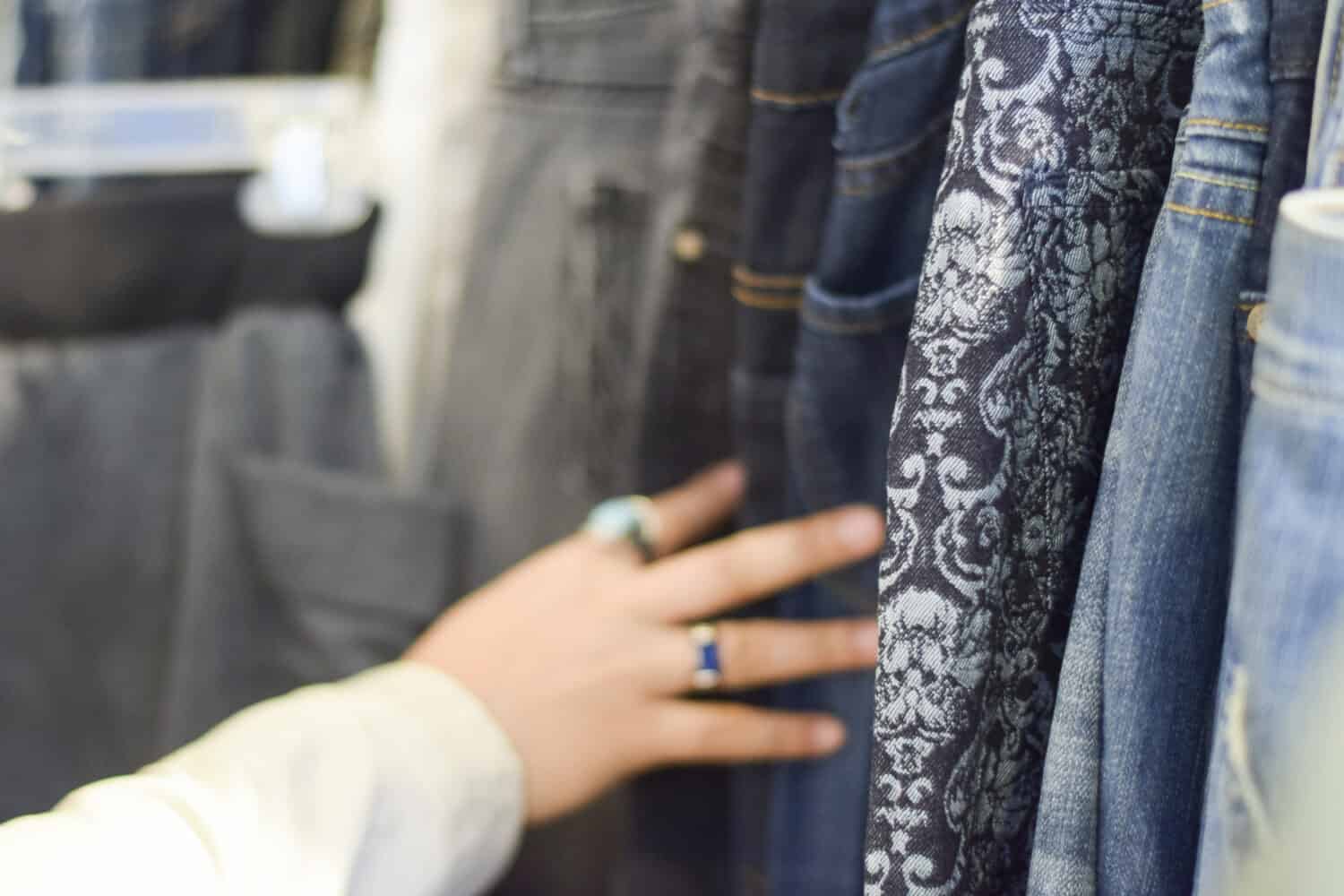 Hand browsing racks of shirts and pants at a stylish boutique