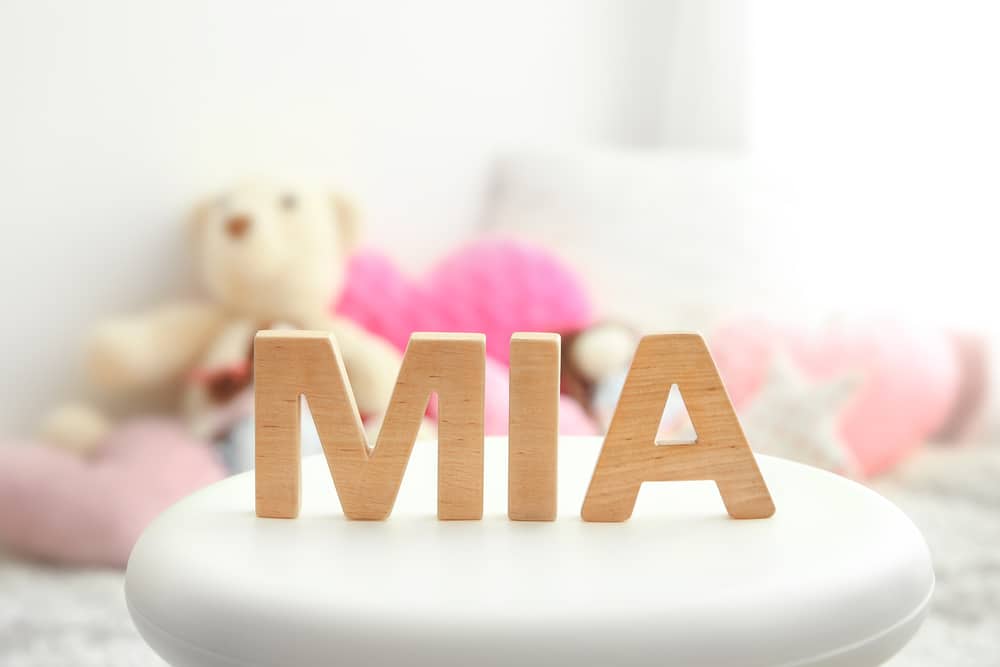 Baby name MIA composed of wooden letters on stool. Choosing name concept