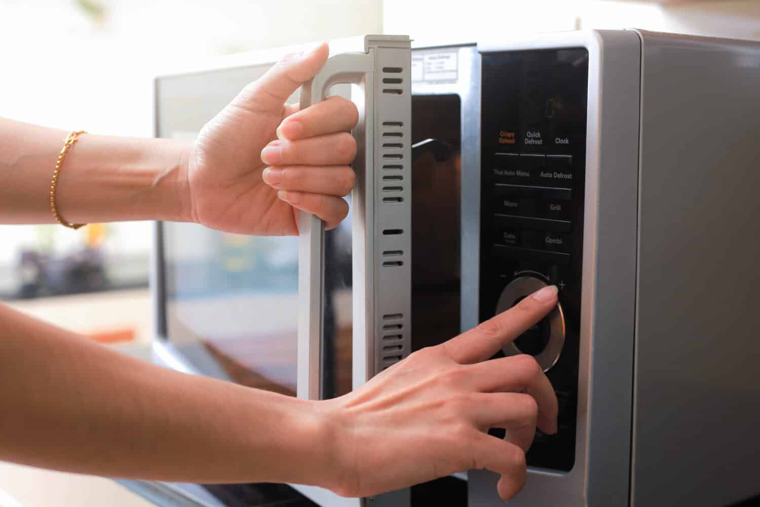 Woman's Hands Closing Microwave Oven Door And Preparing Food in microwave.