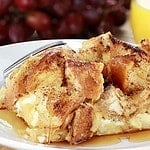 French toast casserole with maple syrup. Made with cream cheese cheese in the center. Fresh grapes and orange juice in background. Extreme shallow depth of field with selective focus on French toast.