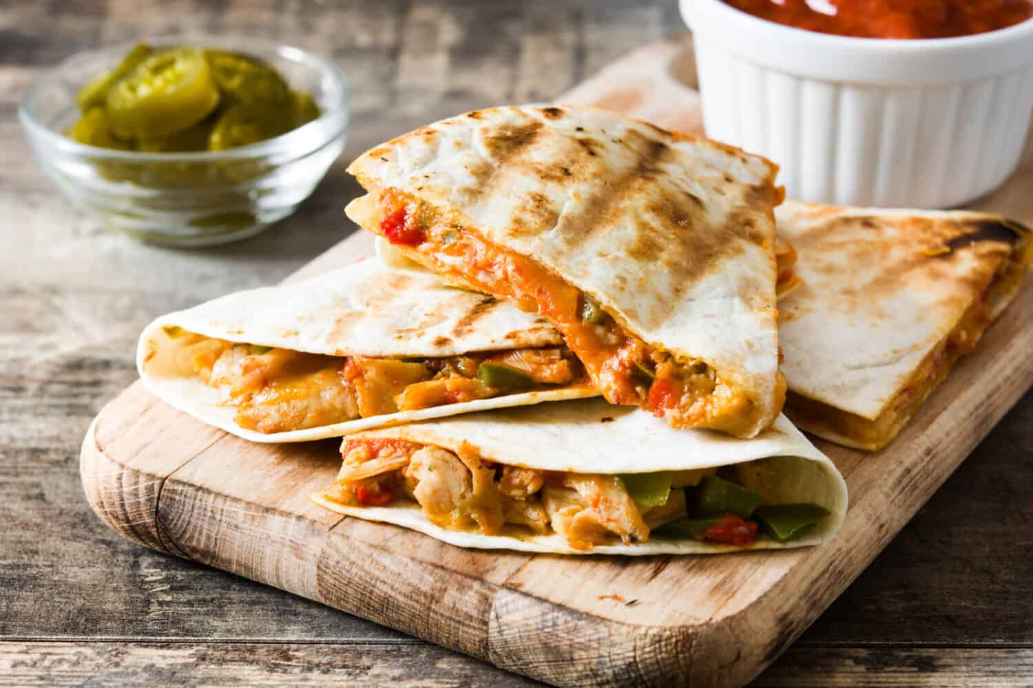 Mexican quesadilla with chicken, cheese and peppers on wooden table.