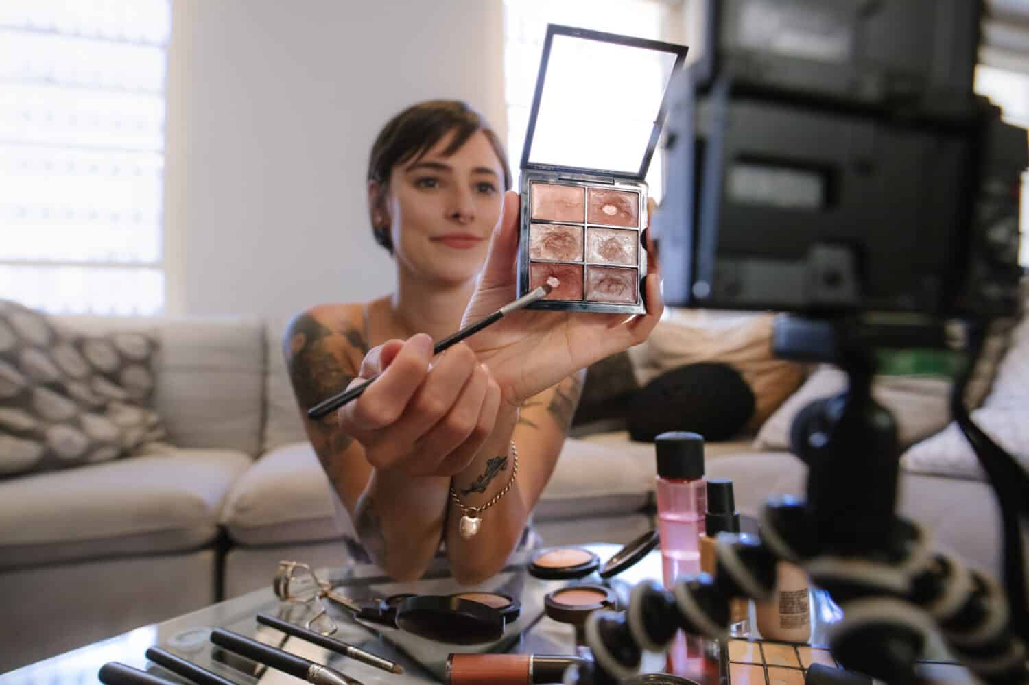 Young woman showing a makeup palette on camera and recording her video. Woman making a video for her beauty blog on cosmetics.