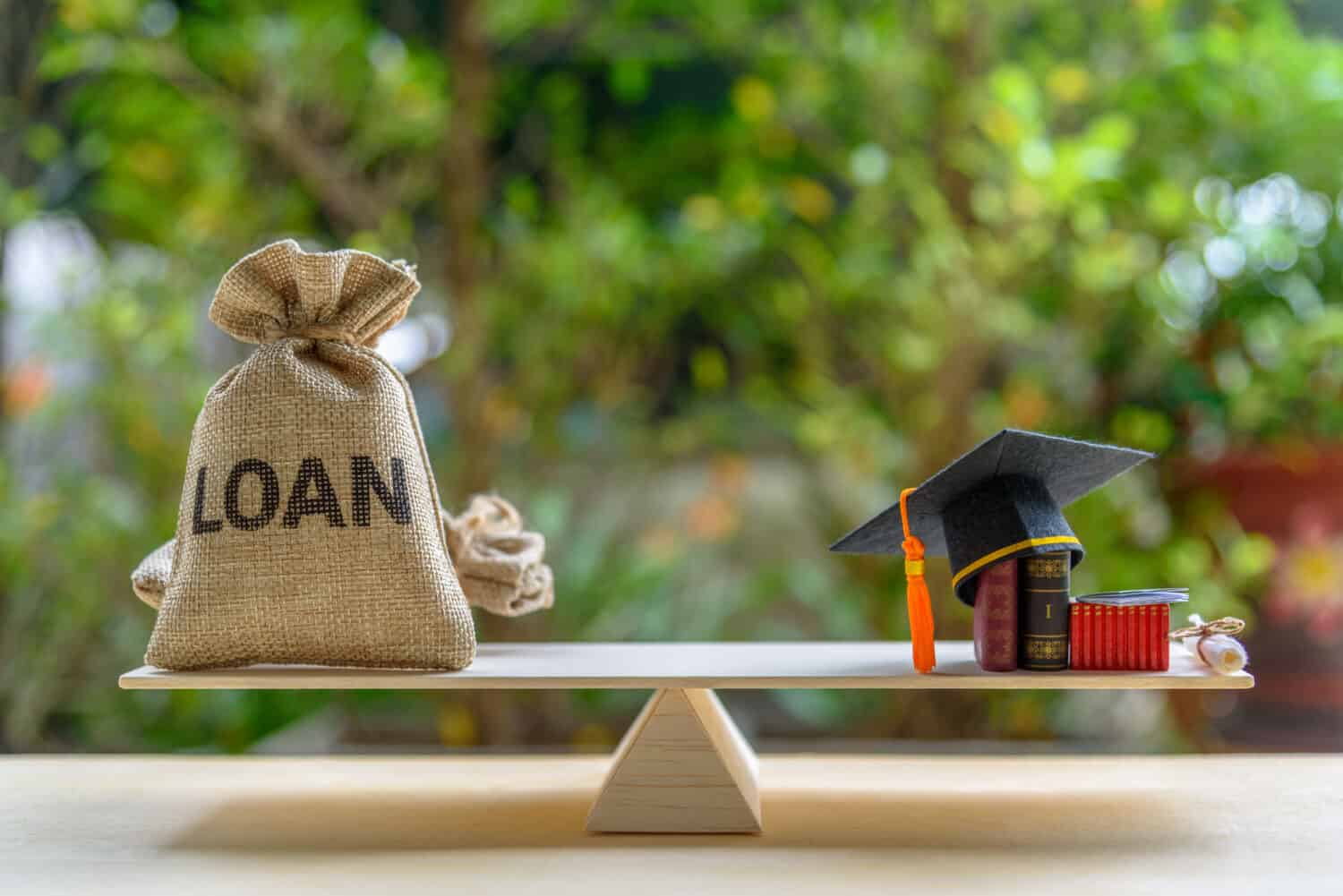 Education loan for study overseas / student loan concept : Mortarboard, loan bag on balance scale, depicts loans issued for the purpose of attending an academic university and pursuing academic degree