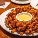 Fried blooming onion with dipping sauce.