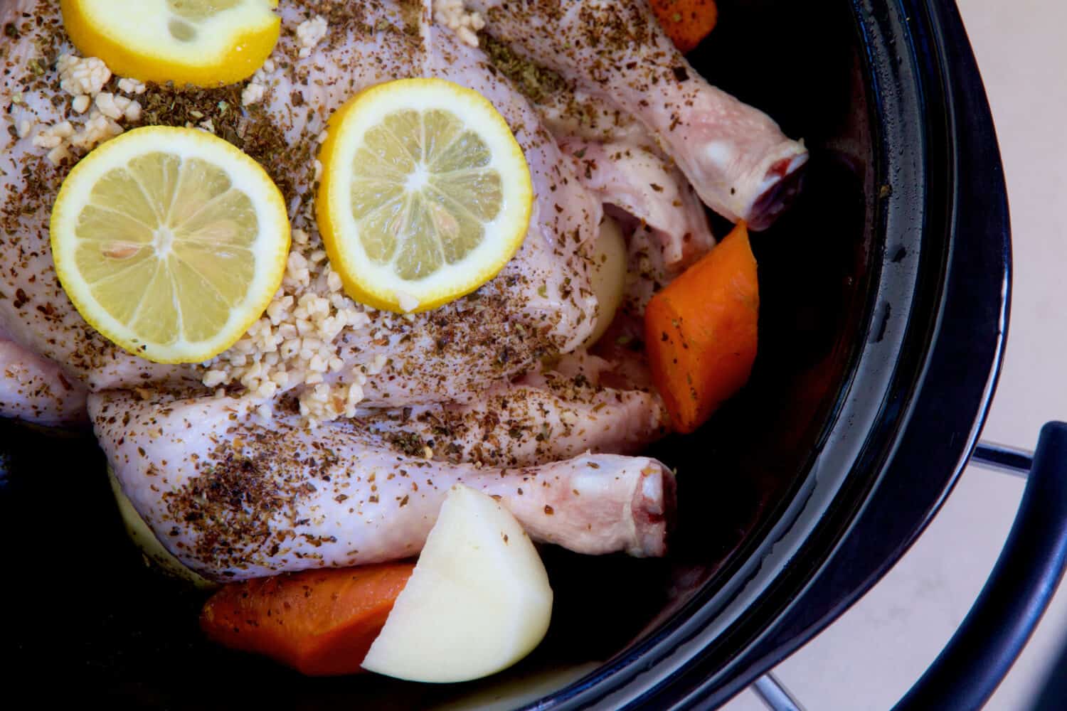Chicken and vegetables with herbs and lemon in a slow cooker.
