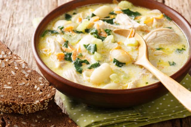 cream soup with gnocchi, chicken and spinach served with bread close-up in a bowl on the table. Horizontal