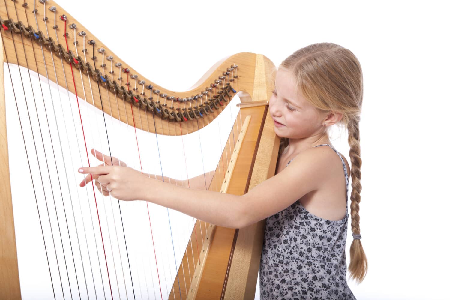young girl in blue playing harp against white background