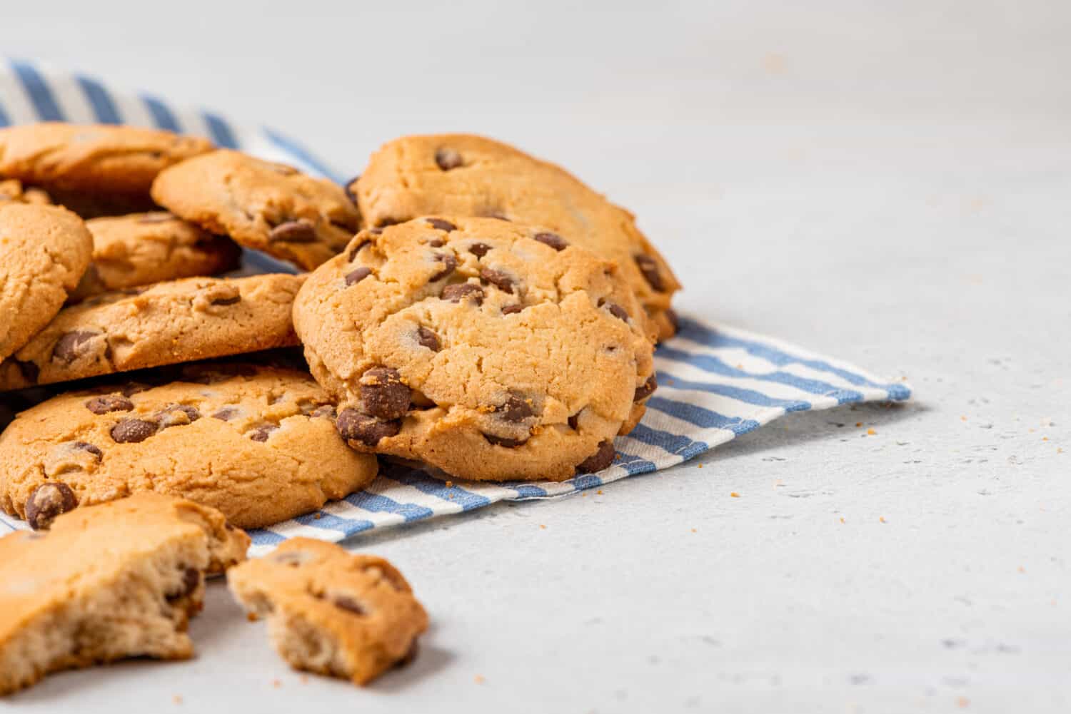 Heap of chocolate chip cookies on a gray table close-up. Sweet breakfast. Stack of traditional chip cookies with chocolate chunks.