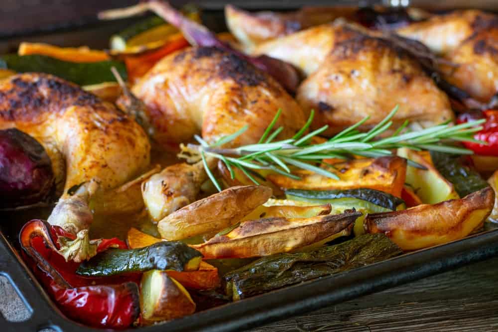 Chicken with oven baked vegetables on a baking sheet
