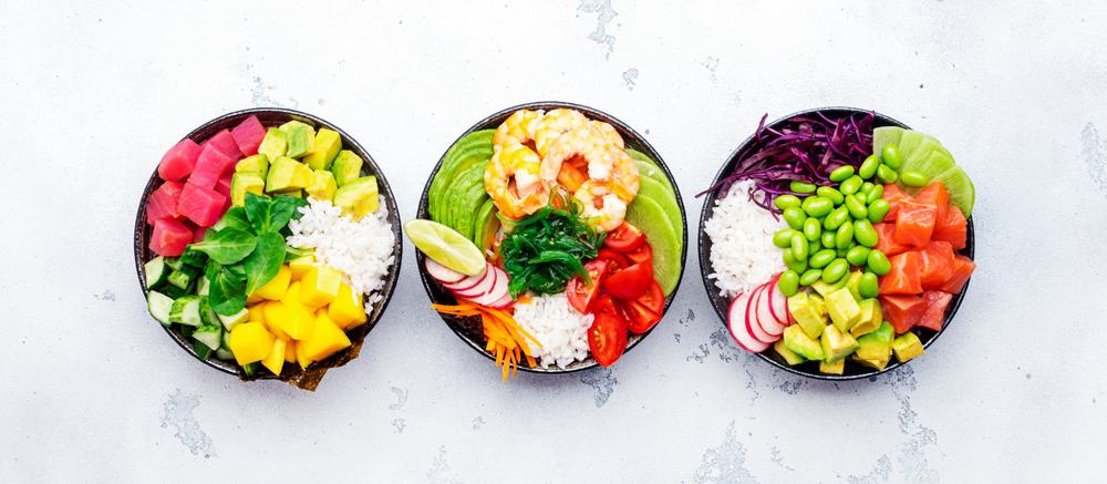 Hawaiian poke bowl set: tuna, salmon, shrimp with avocado, mango, radish, rice and other ingredients. Soy sauce and sesame dressing. White table background, top view banner