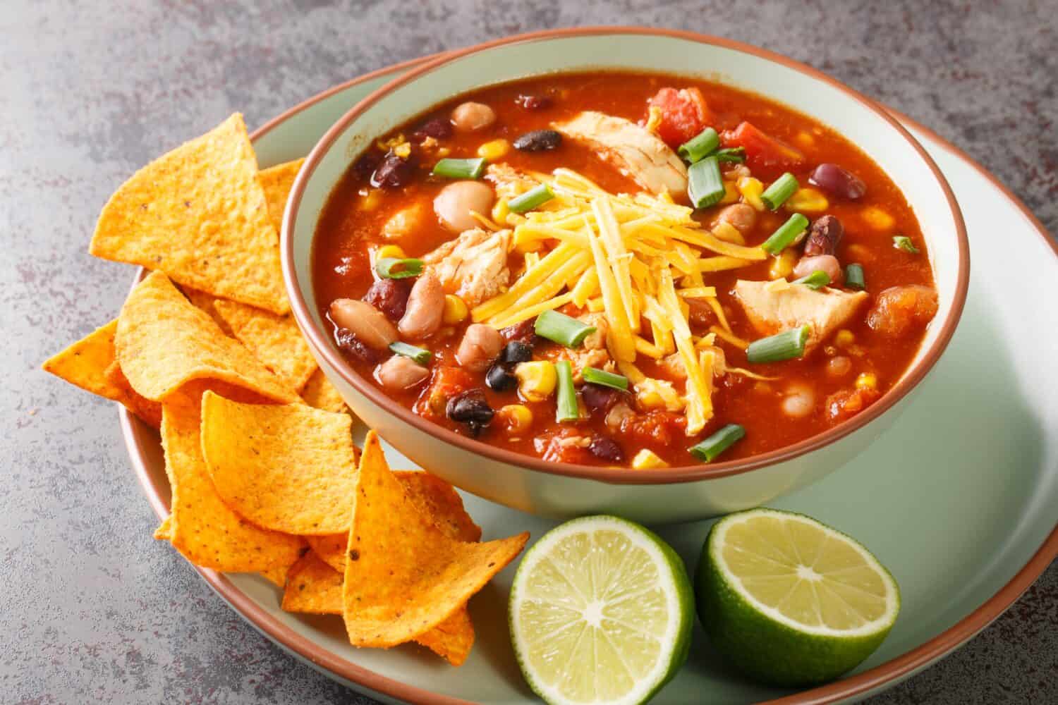 Tasty chicken taco soup full of tender chicken, sweet corn, black beans, fire-roasted tomatoes, and the most delicious creamy broth close-up in a plate on the table. Horizontal