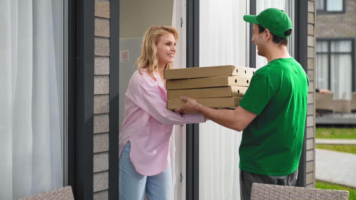 Lot pizza box deliver. Man give many hot pie. Fast food delivery service. Joy girl meet pizzeria courier. Young adult person order take away meal. Tasty pizza home delivery. Online city eat cafe job.
