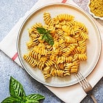 fusili pasta with basil pesto and herbs, italian cuisine, gray stone background. Home made food.