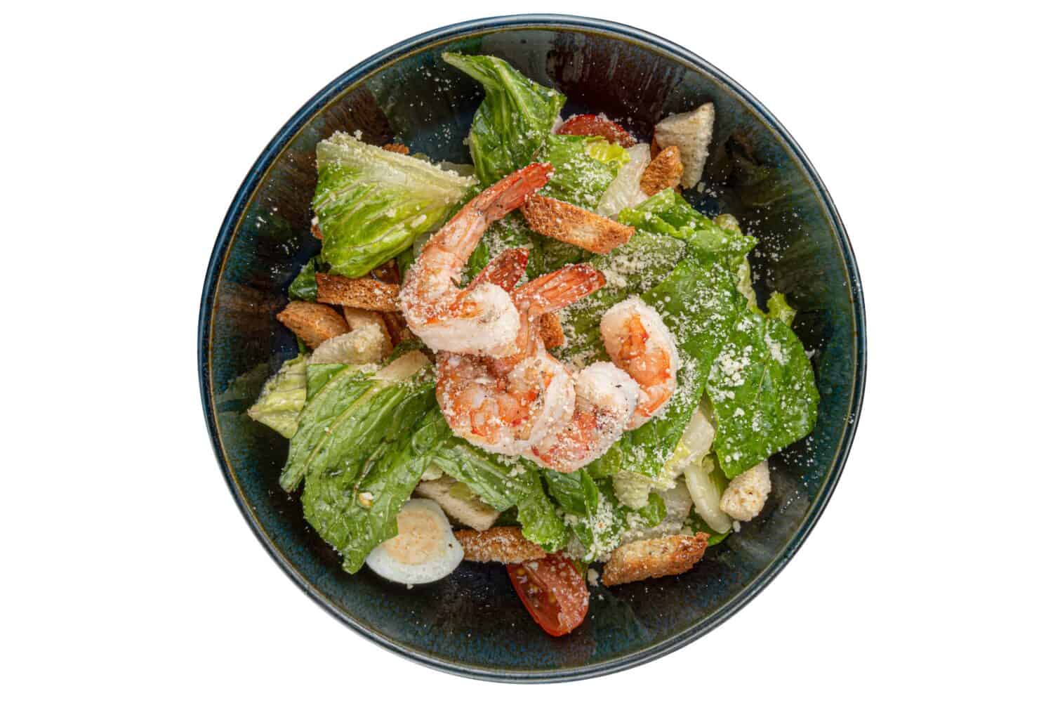 Shrimp Salad. Seafood Caesar Salad served with croutons, shrimps, salad leaf and parmesan on black background. Italian caesar salad.Top view, copy space.
