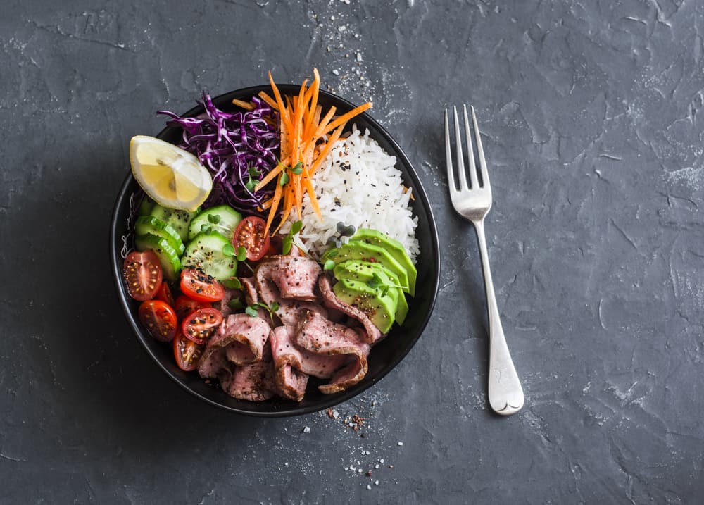 Beef steak, rice and vegetable power bowl. Healthy balanced food concept. On a dark background, top view