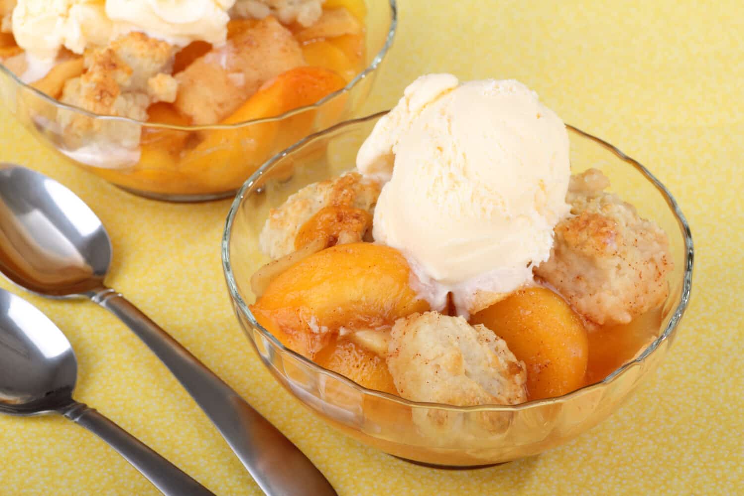 Two bowls of peach cobbler with ice cream on top