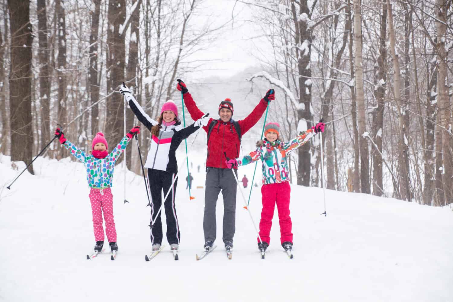 Family with two children cross-country skiing in the winter forest in the snow