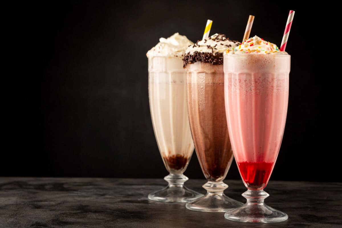 Three glasses of milkshake with assorted flavors. Chocolate, vanilla and strawberry milkshake.