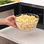 Woman taking bowl of popcorn from microwave oven in kitchen