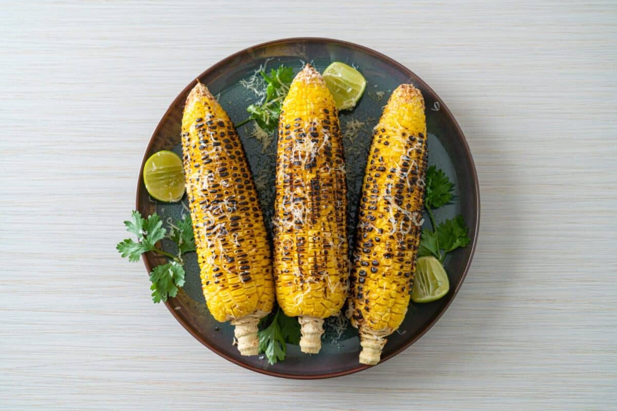 barbecue and grilled corn with cheese and lime on plate