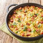 Hash brown of grated potatoes, leeks, eggs and diced smoked bacon close-up in a pan on the table. Horizontal