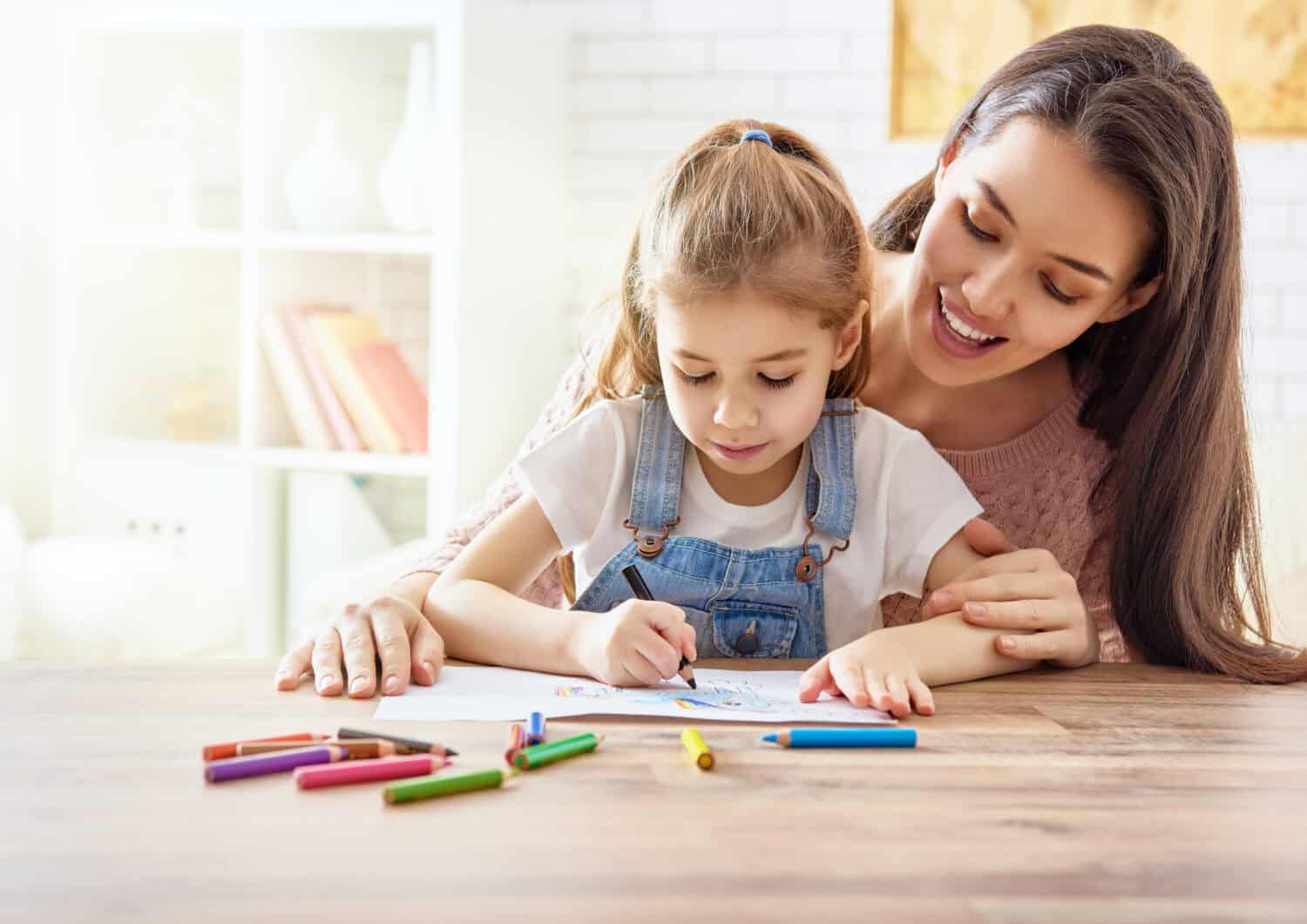 Happy family. Mother and daughter together paint. Adult woman helps the child girl.