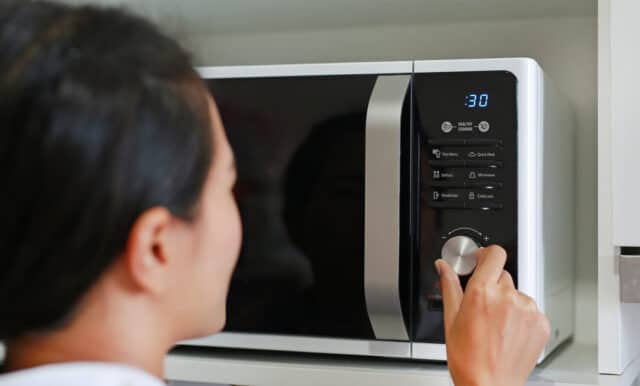 Woman using microwave oven at home.