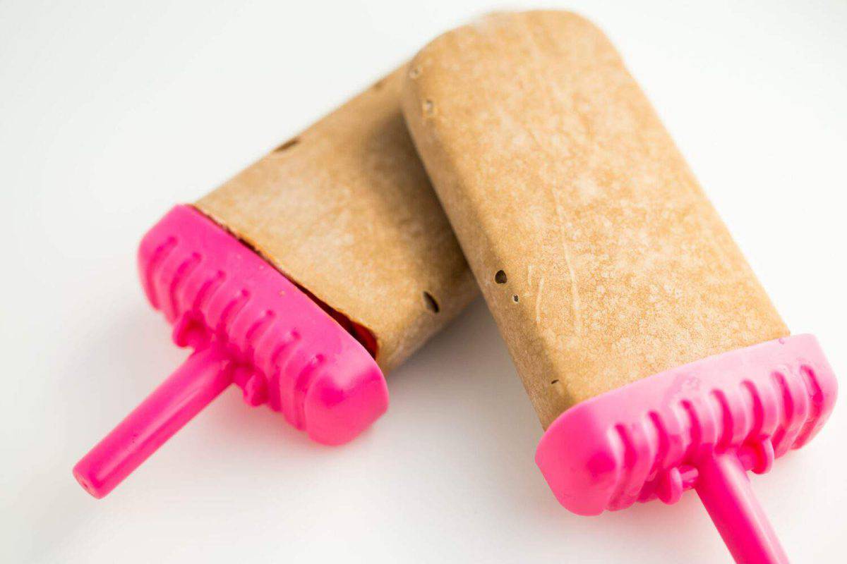 A closeup shot of the homemade tasty frozen pudding pops on the white background