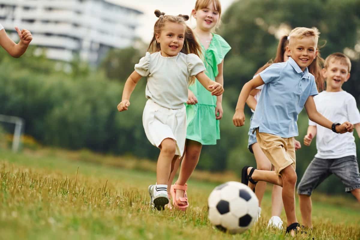 Playing soccer. Kids are having fun on the field at daytime together.