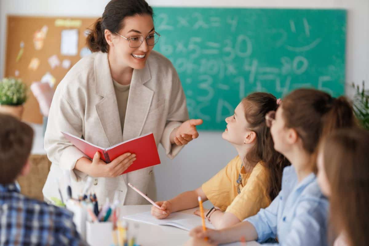Happy kids and teacher at school. Woman and children are working in the class.