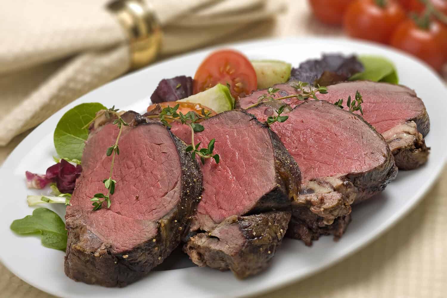 Bison Tenderloin on white plate setting with salad garnishes