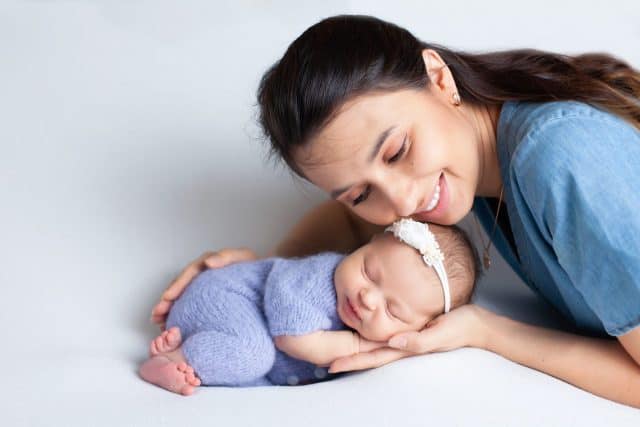 Beautiful young mother with a newborn daughter in a diaper on a white background. Motherhood. Tenderness. Space for text. High quality photo